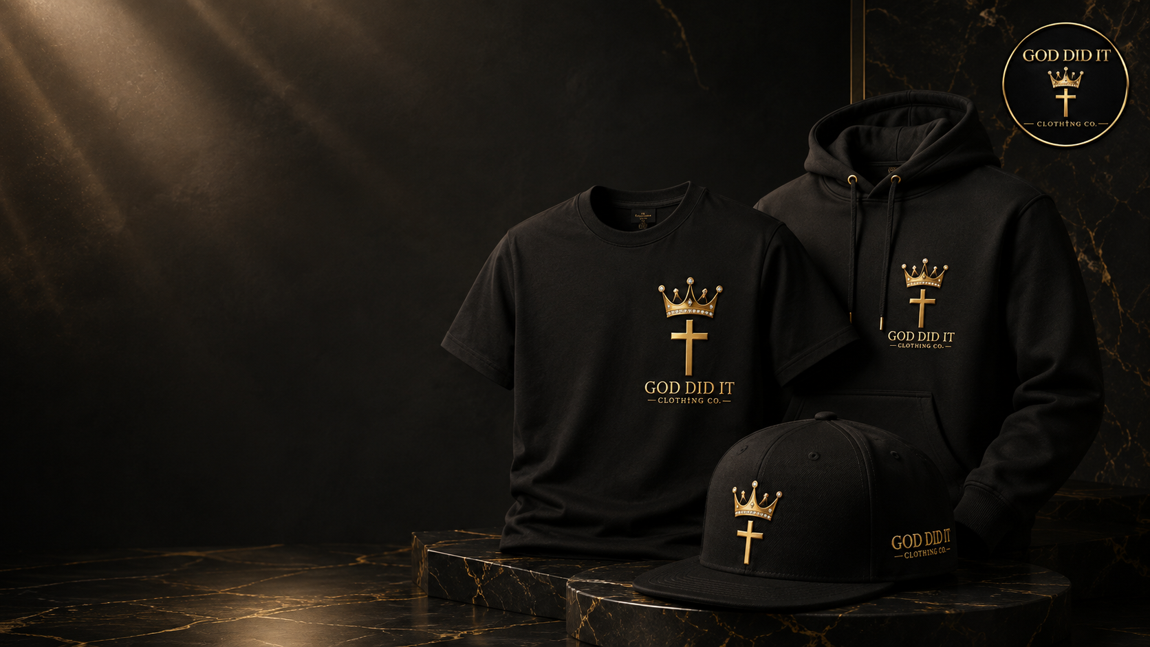 Black GOD DID IT CLOTHING CO. tee, hoodie and cap with gold crown and cross emblems, lit on black marble